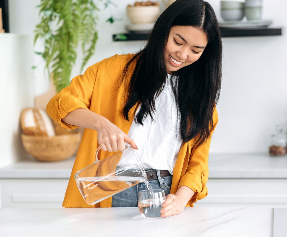 A person pours filtered, safe water into a cup