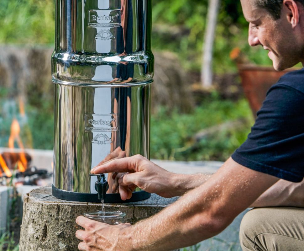 Someone using their Berkey Water Filter while camping outdoors.