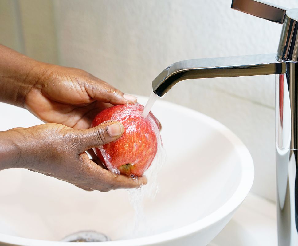How Clean Is Your Tap Water? 9 Signs You Need A Water Filtration System At Home Someone washing fruit under tap water.