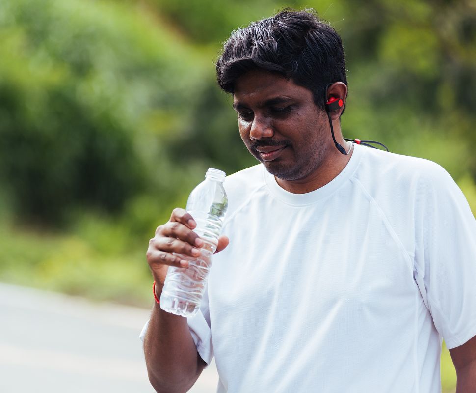 Is Bottled Water A Scam? Let’s Do The Math A runner looks at their bottle of water with concern.