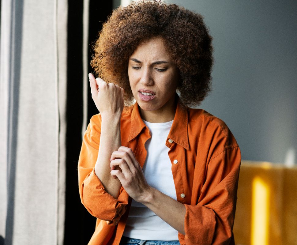 How Chloramine Levels Affect Shower Air Quality & Skin Health Woman scratching the skin on her arms because it itches.